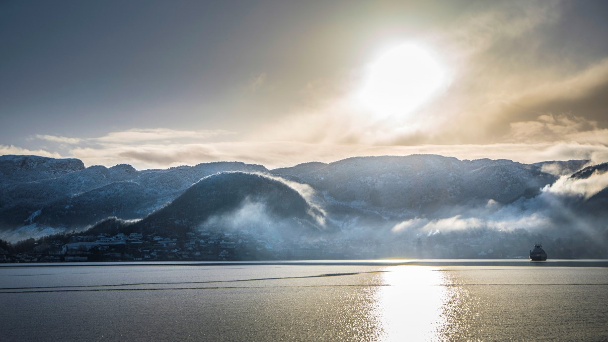 Utsikt over fjorden med ferja i det fjerne.