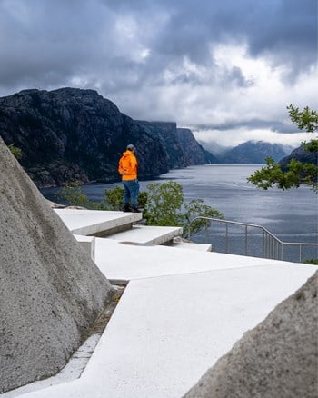 Betongsti går i en kløft av skråninger belagt med betong. Terrenget åpner seg opp med utsikt utover fjorden.