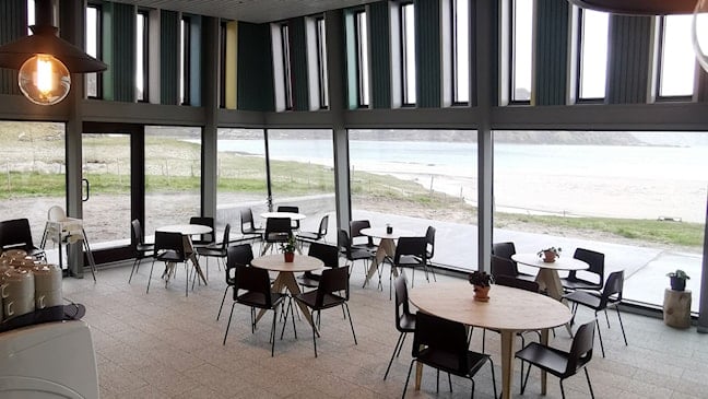 Cafe with views of sandy beach and mountains.