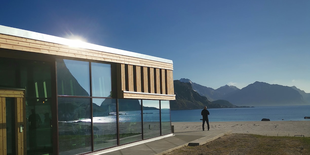 Nature is reflected in the glass facade of the building.