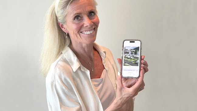 Middeladrende kvinne viser fra en turistside på mobil.