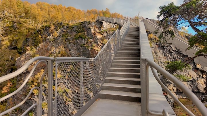 Stålbru omgitt av trær med høstfarger.