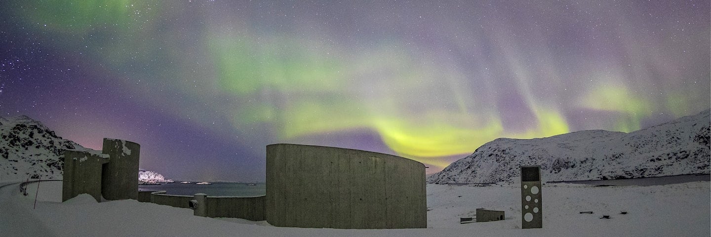 Northern lights over Selvika picnic area with a view of the sea and the road in the landscape