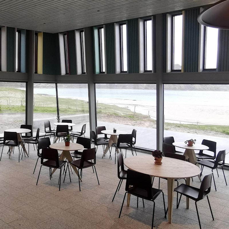 Cafe with views of mountains and white sandy beach.