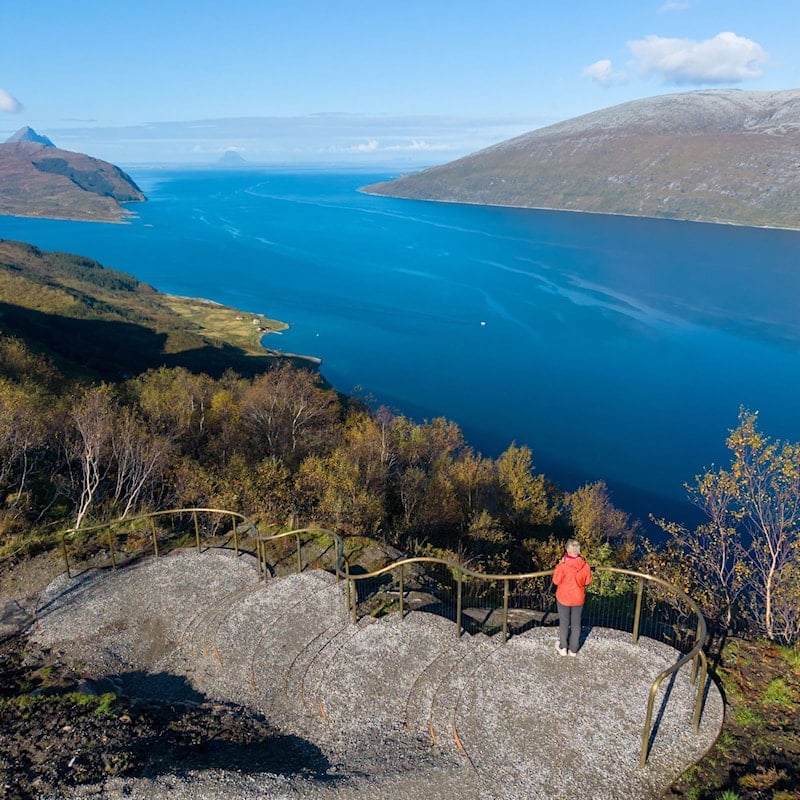 Person ved utsiktspunkt på Sjonfjellet med utsyn over fjord, øyer og fjellandskap.