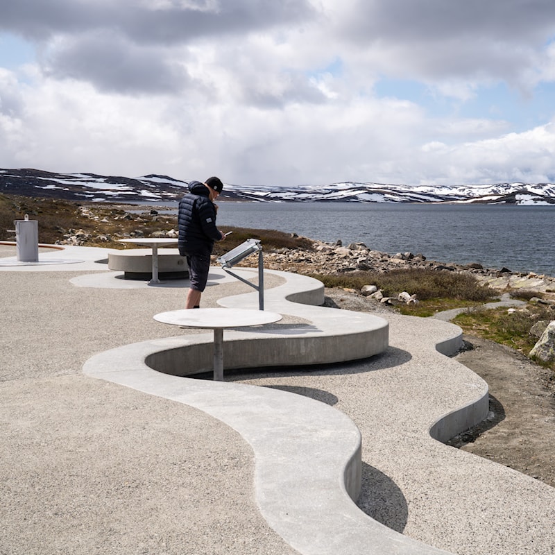 Foto av rasteplass ved innsjøen Ørteren. En mann leser på en tavle.